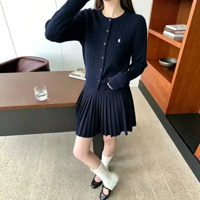 Completo con cardigan scuro e gonna plissettata indossato da una modella; controlla i capi inclusi e le misure.